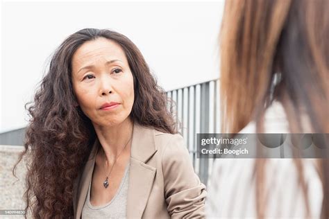 Mature Japanese Woman Listening To Coworker With Look Of Concern High