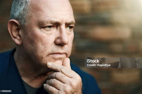 A Senior Man Looks Thoughtful Hand On His Chin As He Stands