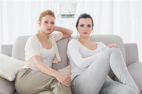Premium Photo Two Serious Female Friends Sitting On Sofa In The