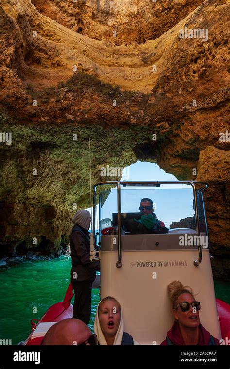 Tourists Enjoying Boat Tour Of Sea Caves On Algarve Coast Portugal