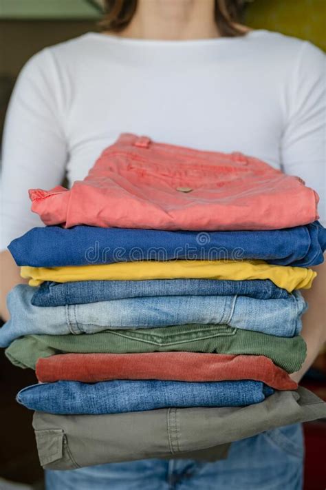 Launder colored items in two groups: Woman Holds Neatly Folded Trousers And Jeans In Bright ...