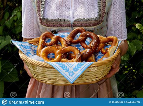 Woman Wearing Bavarian Dirndl Dress Holding Basket Of Pretzels At