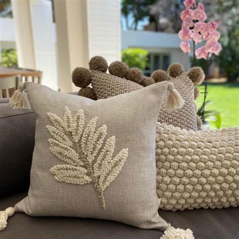 Three Pillows With Pom Poms On Them Sitting On A Couch In Front Of A House