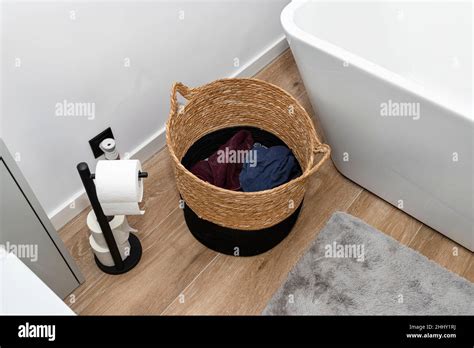 A Wicker Laundry Basket With Dirty Clothes In The Bathroom Next To The