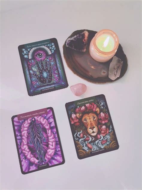 Three Tarot Cards Sitting On Top Of A Table Next To A Candle And Some Rocks