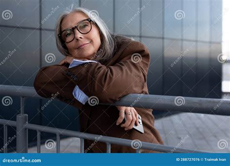 well groomed elderly gray haired business woman in a brown jacket and trousers walks in an urban