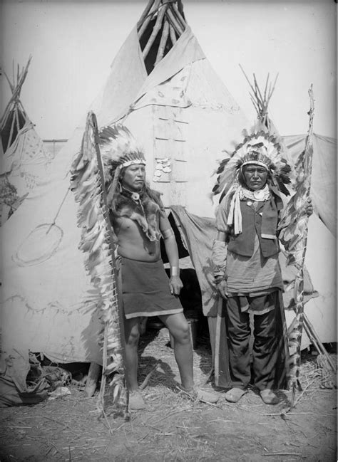 native american plains men pose near a tepee with staffs decorated with feathers 1880 1900
