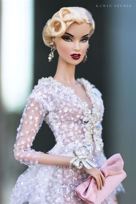 A Barbie Doll Wearing A White Dress And Holding A Pink Handbag In Her