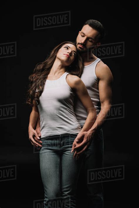 Man Hugging Attractive Woman In White Singlet Isolated On Black Stock