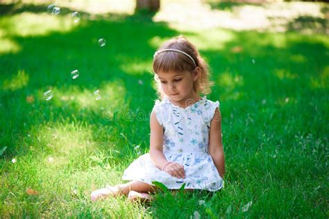 Portrait Of A Smiling Little Girl Sitting On Green Grass Stock Image