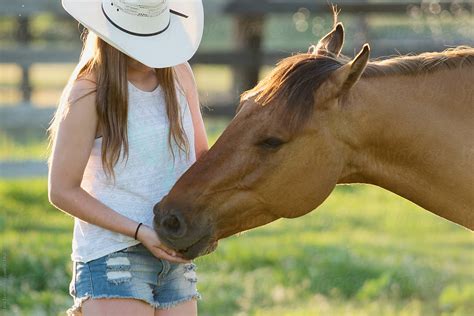 Teen Cowgirl Gives Grain To Her Horse On A Summer Day By Stocksy