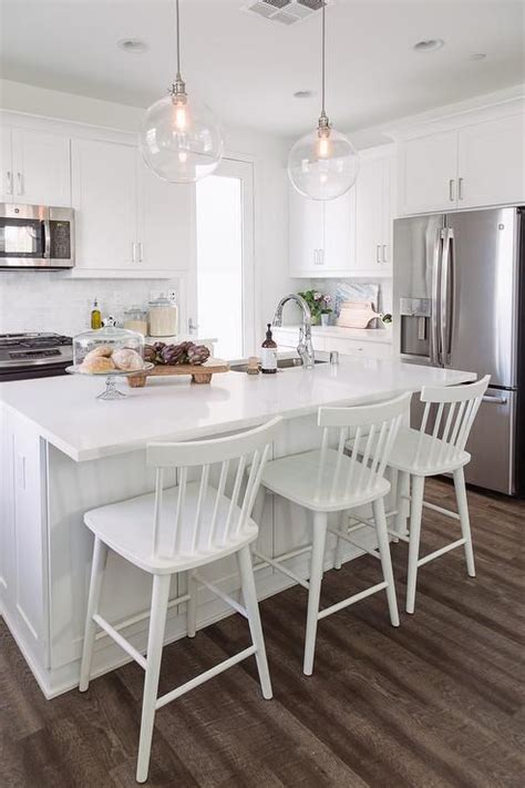 It has been decorated nicely with the wreath, large clock and upholstered stools. Modern counters stools with a farmhouse vibe sits against ...