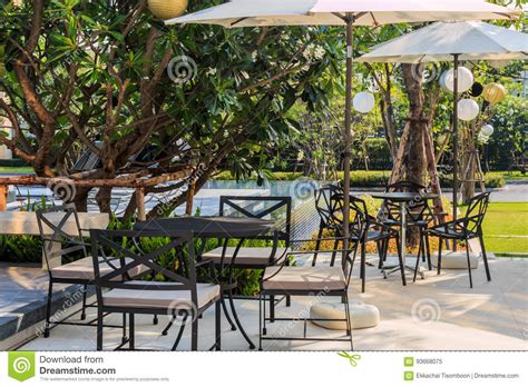 Cafe Tables And Chairs Outside With Big White Umbrella And Plant Stock