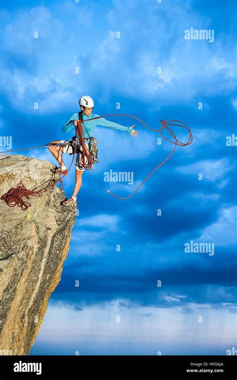 Female Climber Dangeling From The Edge Of A Sheer Rock Mountain Stock