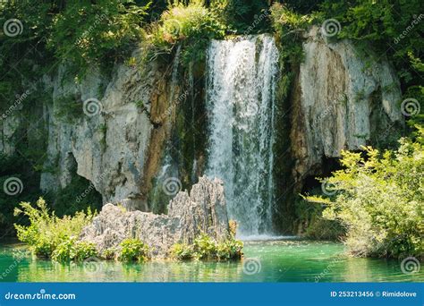 Waterfall Falls From Rock Into Turquoise Water At Sunlight Stock Photo