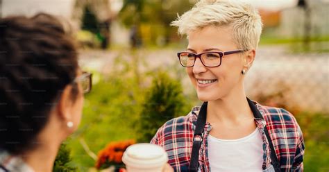 Portrait Of Cute Blonde Short Haired Smiling And Chatting With Colleague While Drinking Coffee