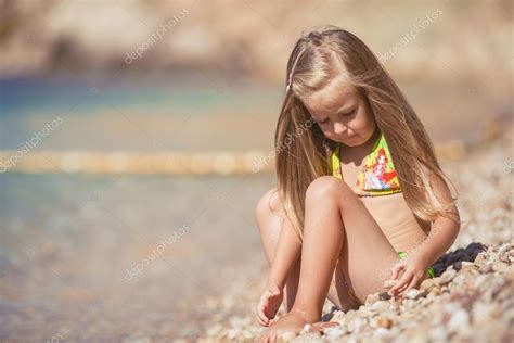 Petite fille assise sur la plage près de la mer image libre de droit