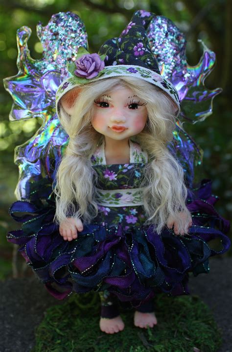 A Doll Dressed Up As A Fairy Sitting On Top Of A Grass Covered Field