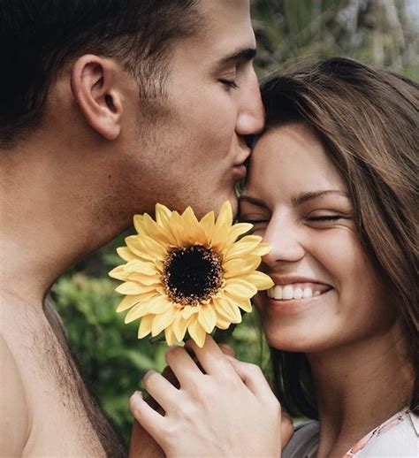 A Man Kissing A Womans Forehead With A Sunflower In Front Of Her