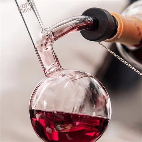 A Red Wine Is Being Poured Into A Flask With A Corkscrew Hanging From It