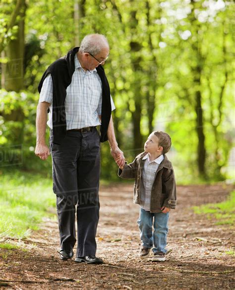 Caucasian Grandfather And Grandson Walking In Woods Stock Photo