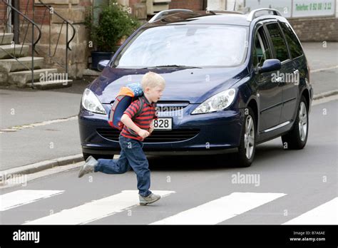 Schoolchild Running Over A Pedestrian Crossing While A Car Is Stock