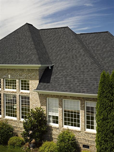 A Large Brick House With White Windows And Black Roof