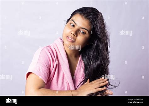 a beautiful indian woman applying hair oil on her black hair with smile on white background