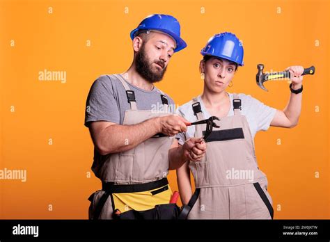 confident constructors holding renovating tools on camera using sledgehammer and pair of pliers