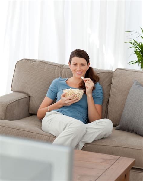 Premium Photo Happy Woman Eating Pop Corn While Watching Television On The Sofa
