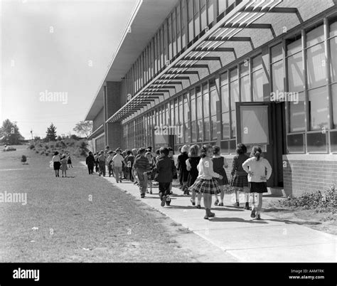 1950s Grade School Children Filing Out Of Side Doors Of School