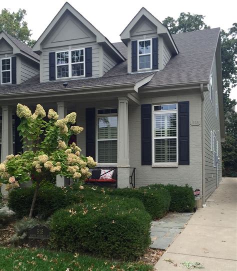 Tan Painted Brick Home With Matching Dormer Siding Black Shutters And