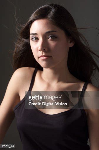 An Attractive Caucasian Woman In A Black Tank Top Tilts Her Head And Looks Forward Into The