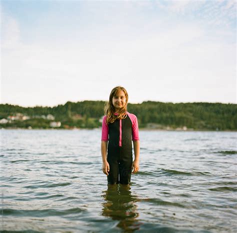 Cute Young Girl Standing In Water With A Wet Suit By Stocksy