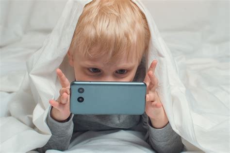 Premium Photo Little Blond Boy Buried His Nose In His Smartphone