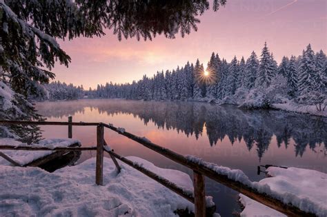Scenic Winter Landscape Of Calm Lake With Wooden Pier Covered With Snow