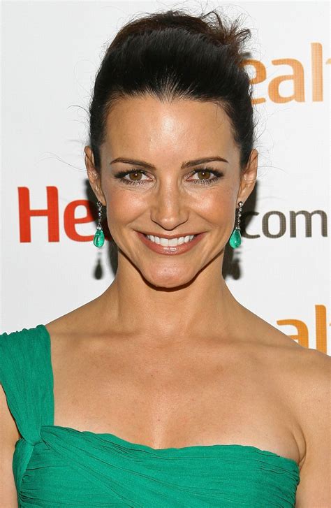 A Woman In A Green Dress Smiling At The Camera With Her Hair Up And