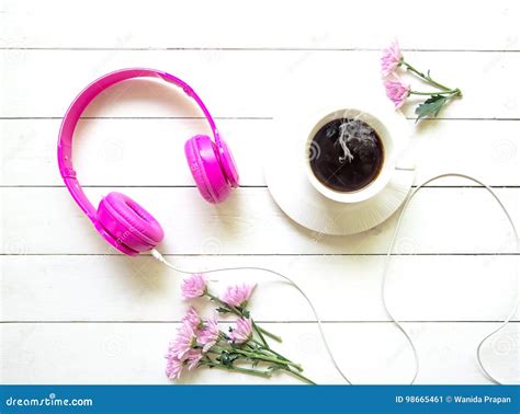 Pink Headphones And Coffee Cup On Wooden Desk Table With Pink Flower