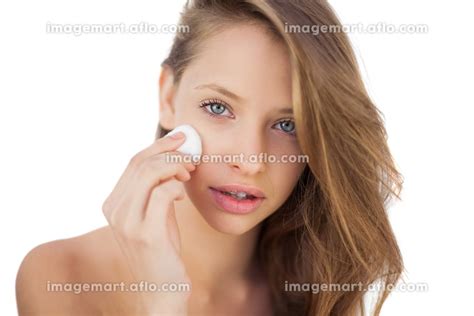 Calm brunette model rubbing her face with cream on white backgroundの写真素材 イメージマート