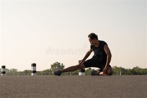 Male Runners Are Stretching The Leg Muscles To Prepare For A Run Stock