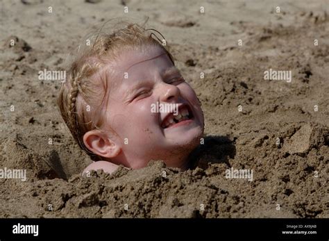 Young Girl Buried In Sand On Beach Watwick Pembrokeshire Wales Uk