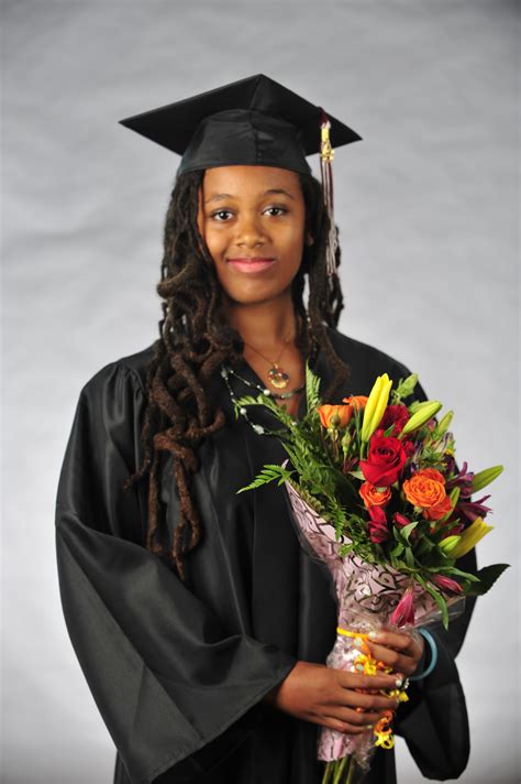 A Woman Wearing A Graduation Gown And Holding A Bouquet Of Flowers In
