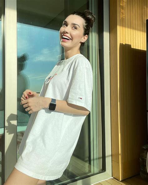 A Woman Standing In Front Of A Window With Her Hand On Her Hip And Smiling