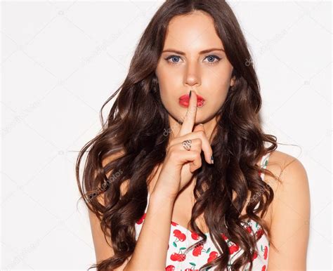 Portrait Of Beautiful Young Woman Pointing Finger To Her Lips Over White Background Concept
