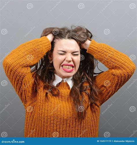 Portrait Of A Hysterical Woman Pulling Hair Out Against Gray Background