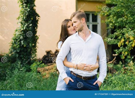 A Happy Girl Hugs Her Boyfriend From Behind And Looks At Him With Loving Eyes Stock Image
