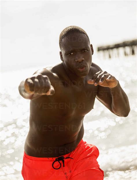 Mixed Race Man Training On Beach Stock Photo