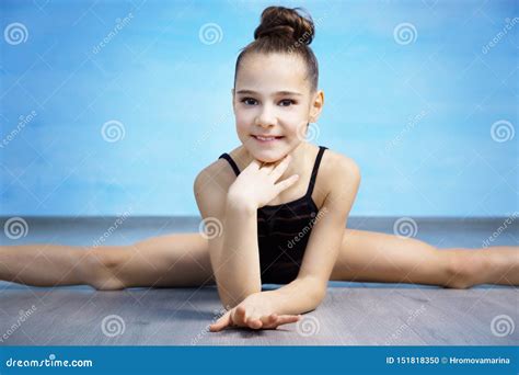 A Portpait Girl Gymnast In A Black Gymnastic Swimsuit Is Sitting On A Cross Splits Stock Photo