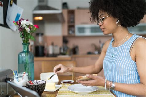 Young Black Woman Having Breakfast Home in Front a laptop with Bread 