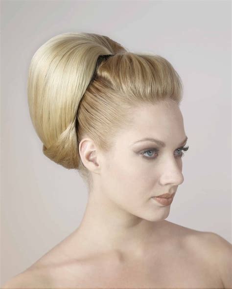 A Woman With Blonde Hair And Blue Eyes Is Wearing A High Bun In Her Hair